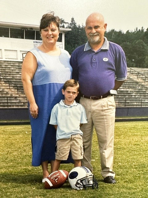 photo of Gary Watkins standing on a football field with his family